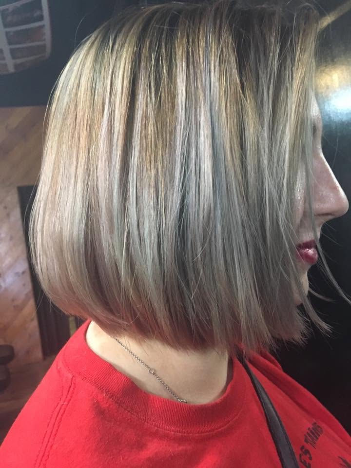 Side-profile portrait of a client with a sleek, chin-length blonde bob featuring dark roots and fine highlights, freshly styled in a salon; polished, confident look.